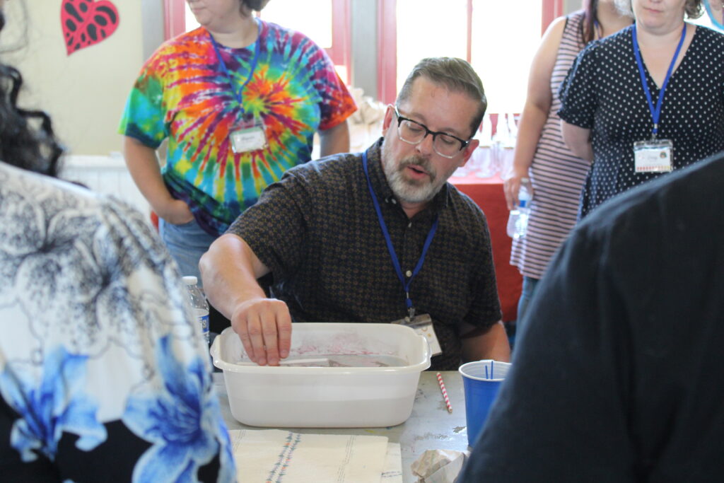 Robert Mahar teaching a paper marblign workshsop with students around him